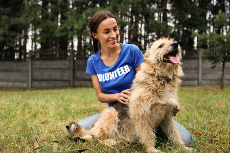 Female volunteer with homeless dog at animal shelter outdoors