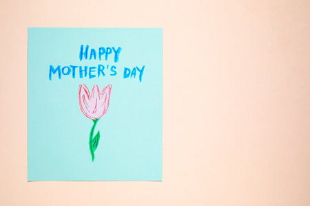 Handmade greeting card for Mother's Day on beige background, top view