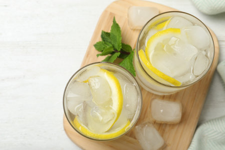 Glasses of cocktail with vodka, ice and lemon on white wooden table, top viewの写真素材