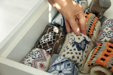 Woman taking warm knitted socks out of drawer indoors, closeupの写真素材