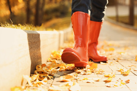 Woman wearing red rubber boots walking in autumn park, closeupの写真素材
