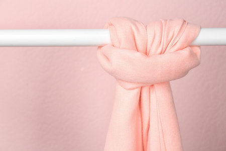 Elegant scarf on wardrobe rack against pink background, space for text. autumn clothesの写真素材