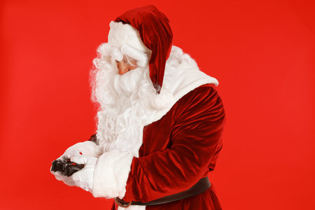 Authentic Santa Claus with game controller on red backgroundの写真素材