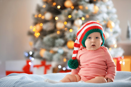 Little baby wearing elf hat on blanket indoors. First Christmasの写真素材