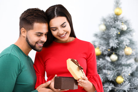 Happy young couple with christmas gift at homeの写真素材