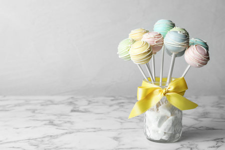 Sweet cake pops on white marble table against gray background. Space for textの写真素材