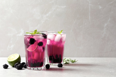 Delicious refreshing blackberry lemonade on light table. Space for textの写真素材