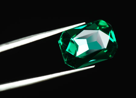 Tweezers with beautiful gemstone on black background. Space for textの写真素材