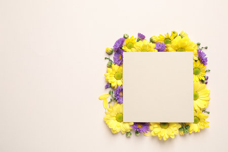 Beautiful chamomile flowers and paper card on beige background, flat lay with space for textの写真素材