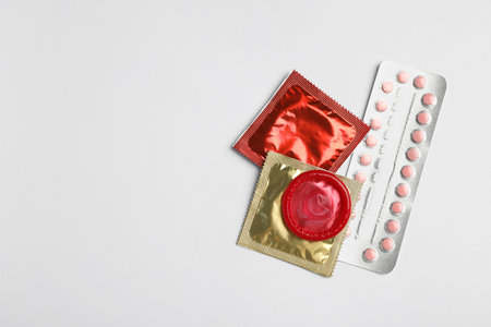 Condoms and birth control pills on light gray background, flat lay with space for text. safe sex conceptの写真素材