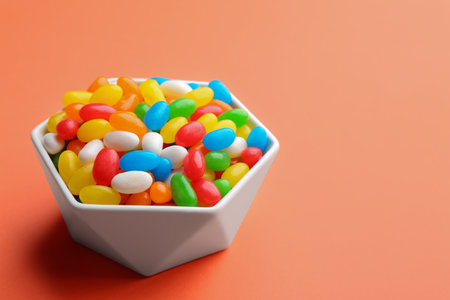 Bowl with colorful jelly beans on coral background. Space for textの写真素材