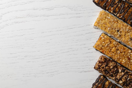 Healthy granola bars on white wooden table, flat lay. Space for textの写真素材