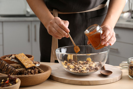 Woman preparing healthy granola bar at wooden table in kitchenの写真素材