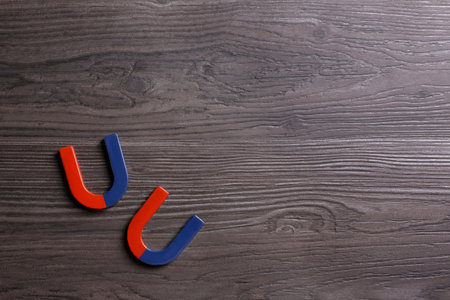 Red and blue horseshoe magnets on dark gray wooden background, flat lay. Space for textの写真素材