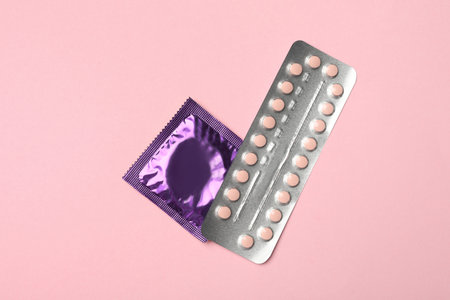 Condom and birth control pills on pink background, top view. safe sexの写真素材