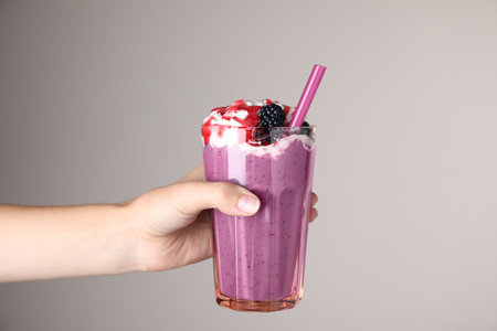 Woman with tasty milk shake on gray background, closeupの写真素材