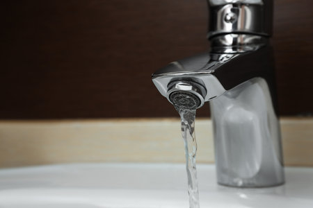 Close up view of water flowing from faucet indoors. Space for textの写真素材