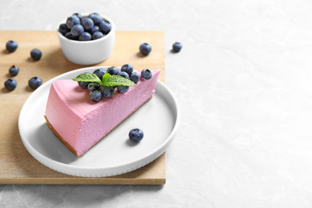 Plate with tasty cake and blueberries on light table. Space for textの写真素材