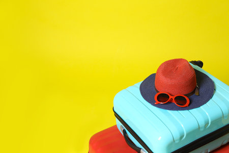 Stylish suitcases and beach accessories on yellow background. Space for textの写真素材