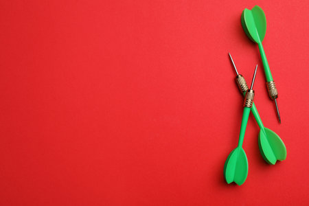 Green dart arrows on red background, flat lay with space for text