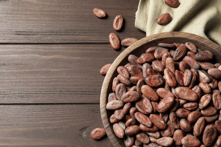 Bowl with cocoa beans on wooden table, top view. Space for textの写真素材