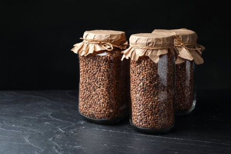 Buckwheat grains in jars on black tableの写真素材