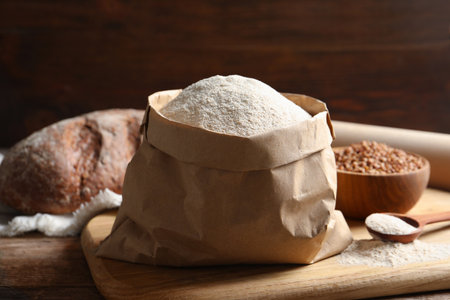 Board with paper bag and spoon of buckwheat flour on tableの写真素材