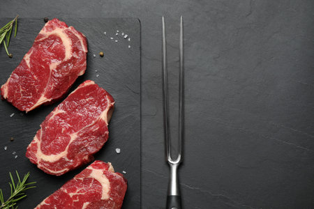 Flat lay composition with fresh meat steaks on dark table. Space for textの写真素材