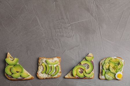 Tasty avocado toasts on gray table, flat lay. Space for textの写真素材