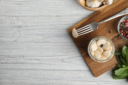 Flat lay composition with jar of pickled garlic on white wooden table. Space for textの写真素材
