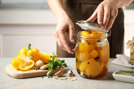 Woman with jar of pickled peppers at table, closeupの写真素材