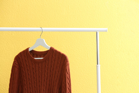 Sweater hanging on rack near yellow wall, closeupの写真素材