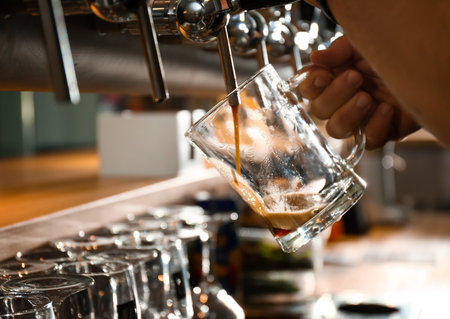 Bartender pouring beer into glass in pub, closeupの写真素材
