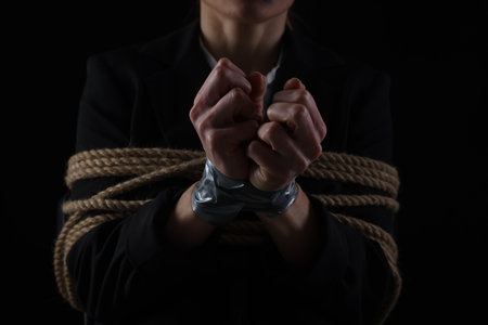 Woman tied up and taken hostage on dark background, closeupの写真素材