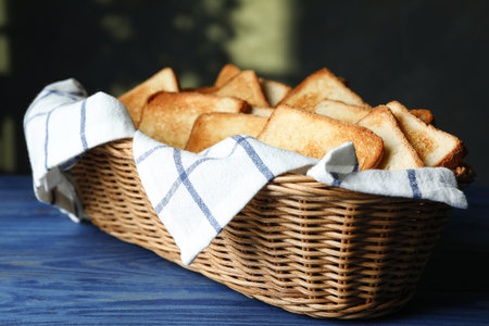 Slices of toasted bread in basket on blue wooden tableの写真素材