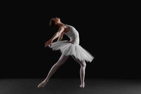 Young ballerina practicing dance moves on black backgroundの写真素材