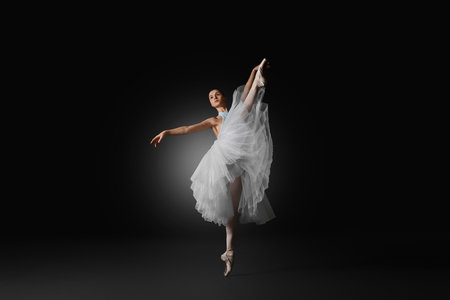 Young ballerina practicing dance moves on black backgroundの写真素材