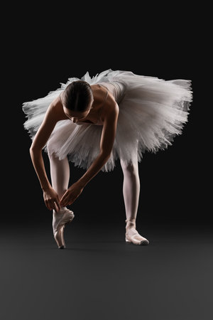 Young ballerina practicing dance moves on black backgroundの写真素材