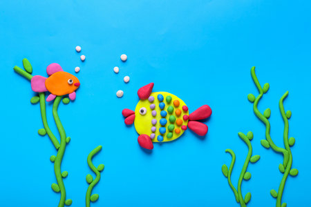 Seaweed and fish made of plasticine on light blue background, flat layの写真素材
