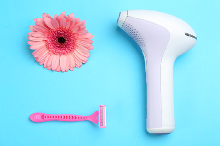 Modern photoepilator, razor and flower on blue background, flat layの写真素材