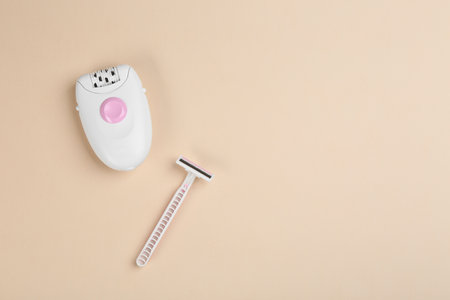 Modern epilator and razor on beige background, flat lay. Space for textの写真素材