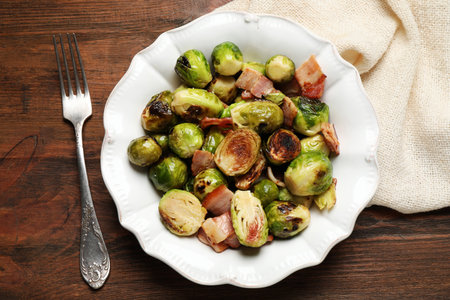 Delicious Brussels sprouts with bacon served on wooden table, flat layの写真素材