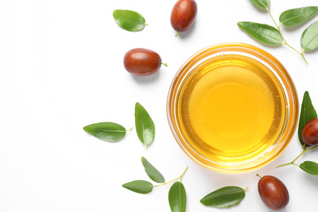 Glass bowl with jojoba oil and seeds on white background, top viewの写真素材
