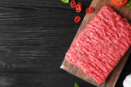 Flat lay composition with fresh raw minced meat on black wooden table. Space for textの写真素材