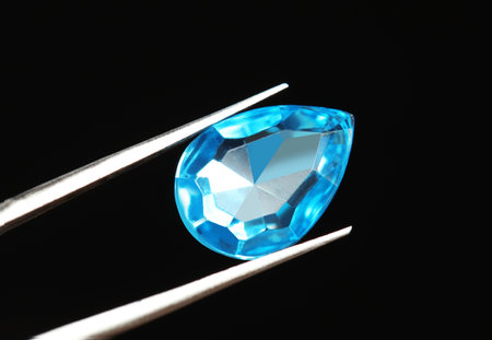 Tweezers with beautiful gemstone on black background