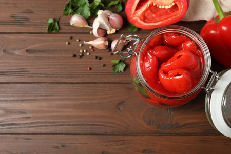 Glass jar with pickled peppers on wooden table, flat lay. Space for textの写真素材