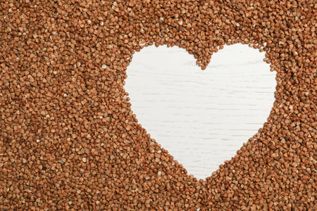 Heart shaped frame made of buckwheat grains on white wooden table, top view. Space for textの写真素材