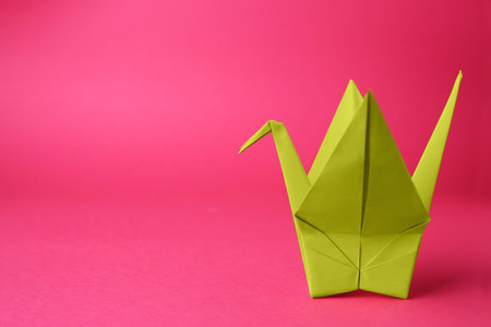origami art. Handmade paper crane on pink background, space for textの写真素材