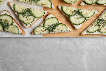 Tasty sandwiches with cream cheese, cucumber and dill on gray marble table, flat lay. Space for textの写真素材