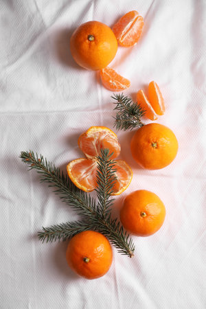 Delicious ripe tangerines and fir branches on white bedsheet, flat layの写真素材
